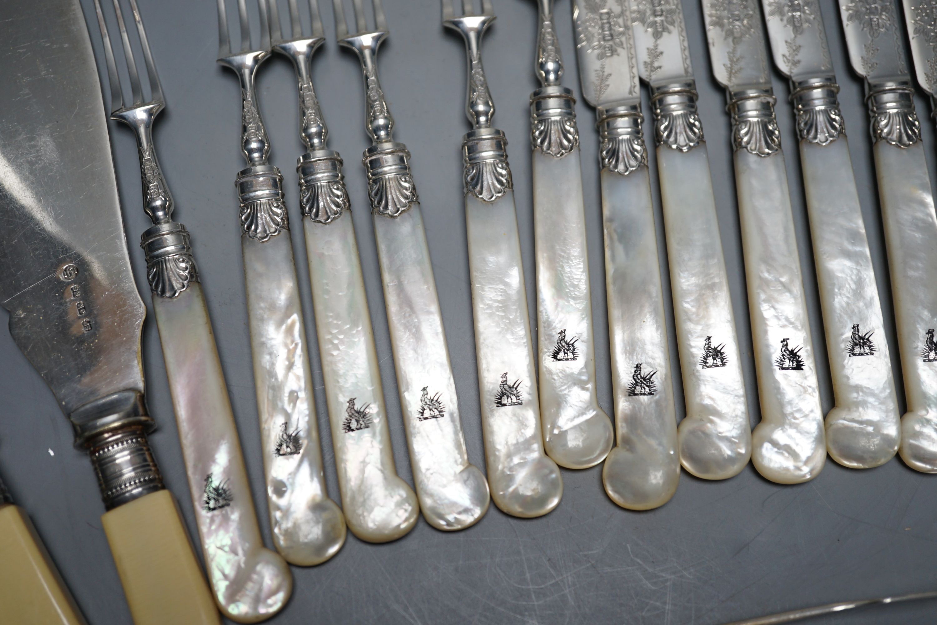 Six pairs of George V mother of pearl handled silver dessert eaters, George Howson, Sheffield, 1921, a pair of silver sugar tongs and assorted plated flatware.